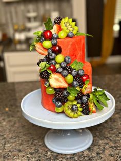 a cake made out of fruit sitting on top of a white plate in a kitchen