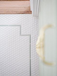 a bathroom with white tile and wooden window sill