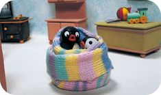 there is a small toy penguin in a crocheted basket with two smaller penguins