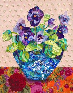 a blue vase filled with purple flowers sitting on top of a colorful tablecloth covered table