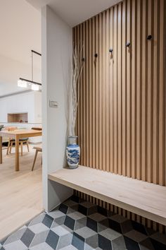 a wooden bench sitting in front of a wall covered with wood slats next to a dining room table