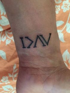 a person with a small tattoo on their wrist that says vai in roman numerals