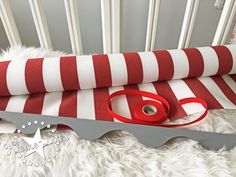 a red and white striped fabric next to a pair of scissors on top of a bed