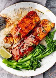 two pieces of salmon and broccoli on top of rice in a white bowl