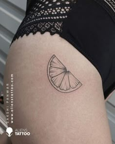 a woman's thigh with a slice of fruit tattoo on her left side ribcage