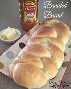 a loaf of bread sitting on top of a white plate next to a bottle of honey