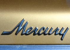 the word'meacuy'written in cursive writing on a shiny gold car