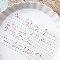 a paper plate with writing on it sitting on a wooden table next to a pen