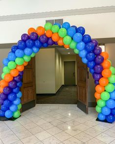 an arch made out of balloons in the middle of a room with tile flooring