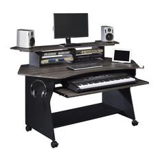 a computer desk with a keyboard, monitor and speakers on it's stand up shelf