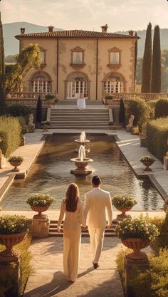 a man and woman walking in front of a large building with water features on it