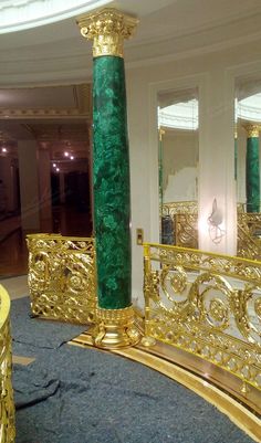 a gold and green pillar in the middle of a room