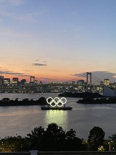 the olympic rings are lit up in front of the city skyline