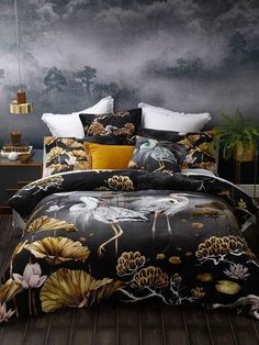 a bed covered in black and yellow comforter next to a night sky with clouds