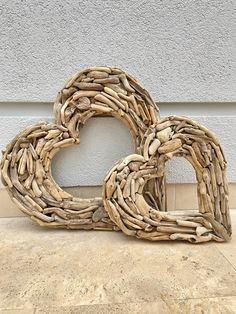 two heart shaped driftwood pieces sitting on the ground in front of a building with a stucco wall behind them