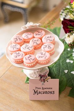 pink lemonade macaroons are sitting on a white platter next to flowers