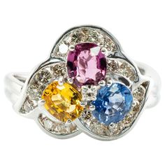 This gorgeous estate ring is finely crafted in solid 14K White Gold and set with genuine Earth mined Sapphires: blue, pink, and yellow gems. Each oval cut stone measures 5mm x 4mm totaling 1.35 carats. These amazing gems are so clean, clear, and transparent, with great intensity and strong brilliance. 18 surrounding diamonds are SI1 clarity and I color totaling .45 carat. Plus one .02 carat single cut diamond of VS1 clarity and G color in the middle. The top of the ring measures 13mm top to bott