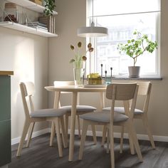 a table and chairs in front of a window with potted plants on the windowsill