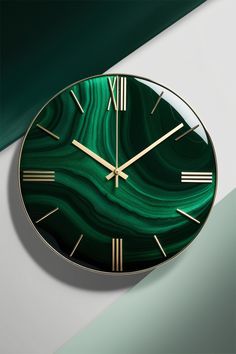 a green clock with gold hands on a white and green wall behind it is an abstract background