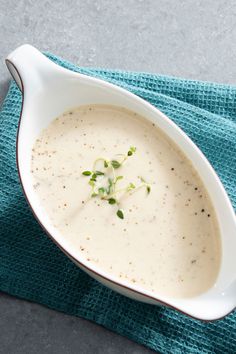 a white bowl filled with soup sitting on top of a blue cloth next to a spoon