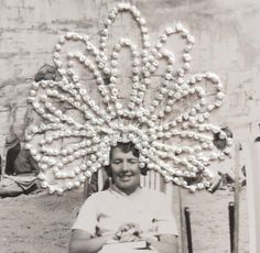 a man sitting in a chair with pearls on it's head and arms around his neck