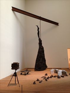 a sculpture is on display in a room with wooden floors and white walls, including a tripod