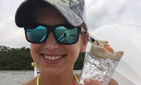 a woman in sunglasses and a hat holding up a piece of tin foil with food on it