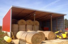 large bales of hay are stacked in the back of a barn with a tractor parked next to it