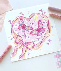 some crayons are laying on top of a paper with a heart and two butterflies