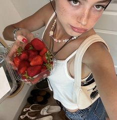 a young woman holding a bowl of strawberries