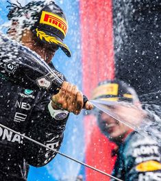 a man is spraying water on himself while another man holds his hand out to him