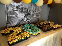 a table topped with lots of cupcakes covered in blue and yellow frosting