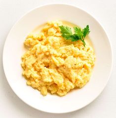 scrambled eggs on a white plate with parsley