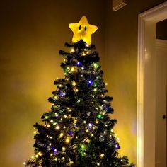 a decorated christmas tree in the corner of a room with lights on it and a yellow star