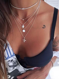 a close up of a woman wearing multiple necklaces on her chest and holding an object in her hand