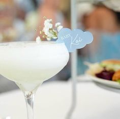 a white table topped with a cocktail glass filled with liquid and garnished with baby's breath