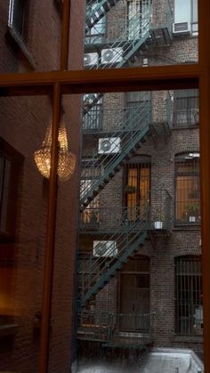 an apartment building seen through a window with snow on the ground and stairs leading up to it