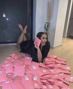 a woman is laying on the floor with pink bags in front of her and holding a cell phone up to her ear