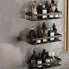 two black shelves with bottles and soaps on them against a wall in a bathroom