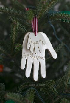 an ornament hanging from a christmas tree that says, ama and someone's hand