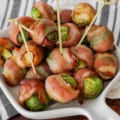 bacon wrapped brussel sprouts with toothpicks in a white dish