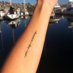 a person's arm with a tattoo that says, i love you and is in front of boats