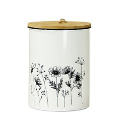 a white and black canister with flowers on the side is holding a wooden lid