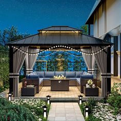 an outdoor living area with couches, tables and lights on the gazebo at night