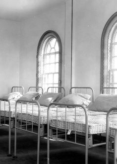 a row of beds in a room with arched windows