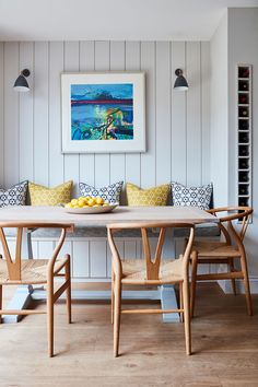 a dining room table with two chairs and a bowl of lemons on it