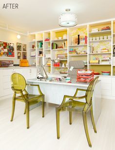 a room with two green chairs sitting at a table in front of bookshelves