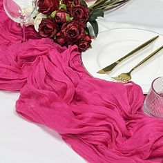 the table is set with white plates and pink napkins