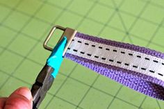 someone is cutting the edge of a purple and white knitted belt with a pair of scissors