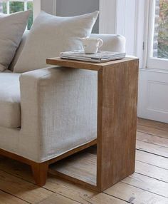 a white couch sitting next to a wooden table on top of a hard wood floor